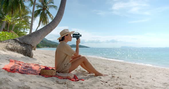 Woman Filming on Camera During Her Picnic on the Beach She Seats on the Sand and Enjoys the Moment alt
