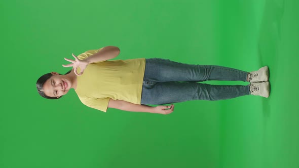 Full Body Of A Happy Young Asian Kid Girl Showing Okay Gesture To The Camera In The Green Screen alt