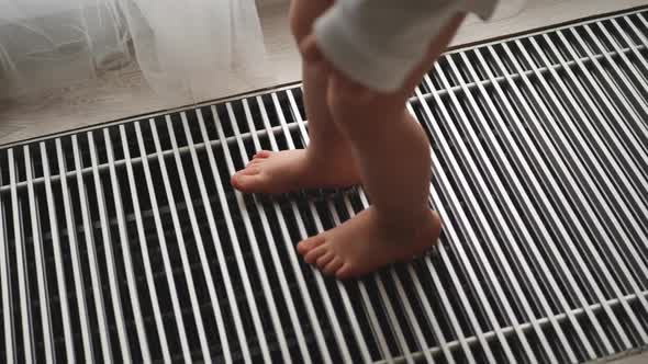 Child Feet Walk Barefoot on the Floor with the Battery in the Floor