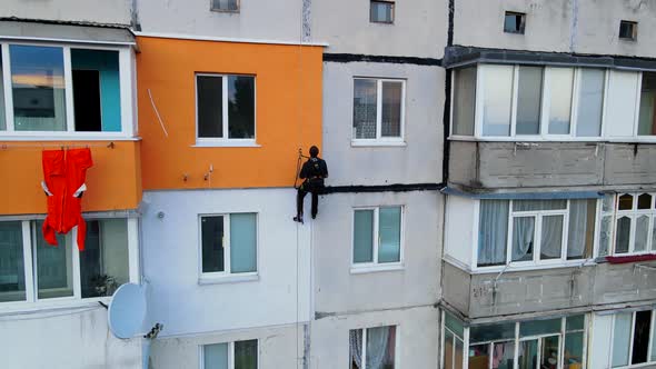 Painting and Decorating Buildings. Worker on a Construction Site of a High-rise Building. Dangerous alt