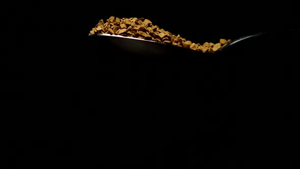 Instant Coffee Pieces Falling From Spoon in Slow Motion on Black Background