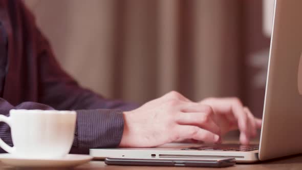 Male Hands Typing a Text on His Laptop on a Coffee Break alt