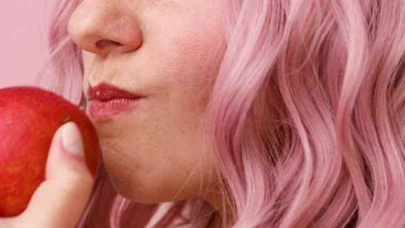 Attractive Young Pink Hair Woman Eating Apple Isolated Over Pink Background