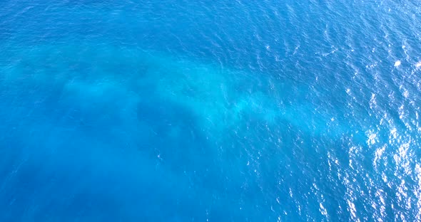 Wide angle aerial clean view of a sandy white paradise beach and blue sea background in colourful 4K alt