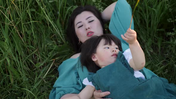 Koreans Family Mother and Daughter in Green Dresses Sitting in the Long Grass alt