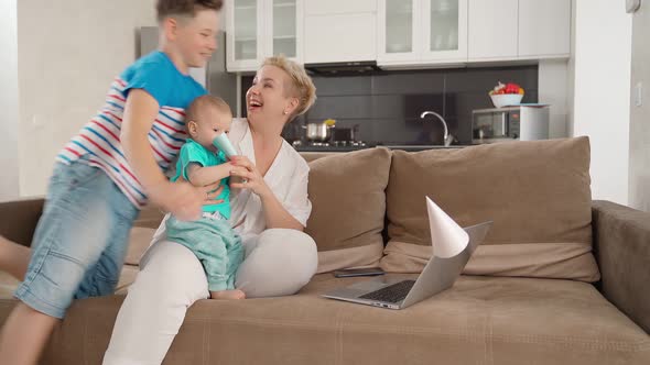 Woman Sitting on Couch with Sons and Having Video Call alt