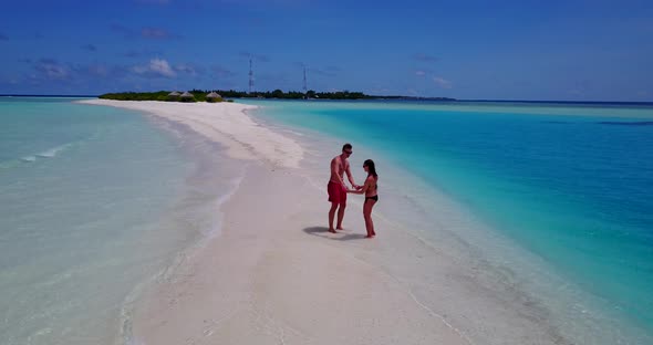 Beautiful boy and girl on honeymoon vacation enjoy life on beach on white sand 4K background alt