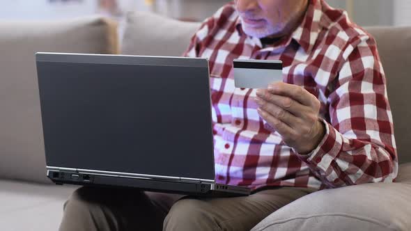 Mature Man Inserting Number of His Credit Card on Laptop to Easy Account Access alt
