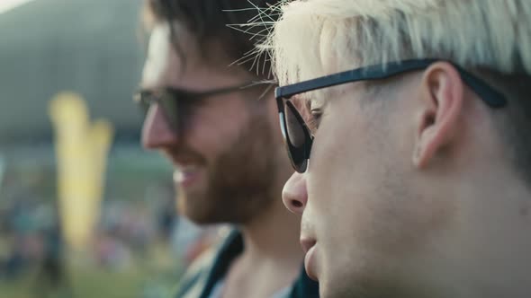 Close up of two young caucasian men having fun on music festival while drinking beer. Shot with RED alt