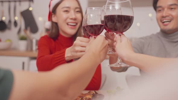 Asian young couple and family clinking wine glasses on table, have christmas party together at home. alt