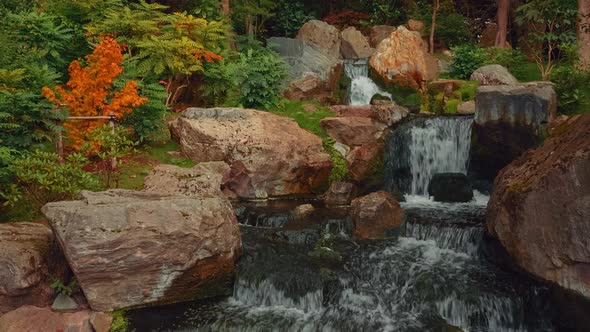 Closeup shot of an exquisite lush Japanese garden with a waterfall in early autumn alt