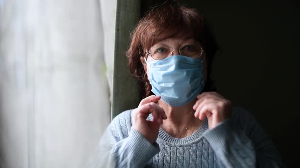 woman puts on a medical mask then removes the mask and sighs with relief alt