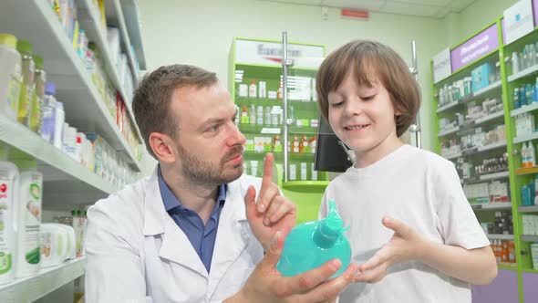 Mature Male Pharmacist Talking To a Little Boy at Drugstore