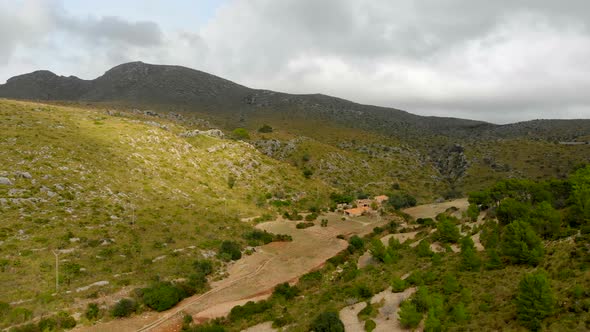 Drone footage moving towards the mountains with a green hill in the foreground. Filmed in realtime a alt