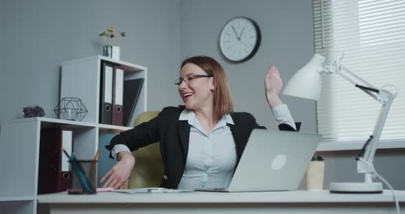 Businesswoman Dancing While Sitting at Her Desk Celebrating Record Sales alt