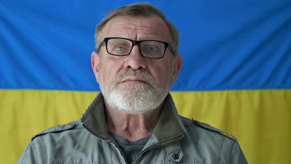Elderly Grayhaired Man Against the Background of the Flag of Ukraine