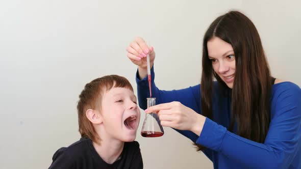 Mother and Son Do a Chemical Experience with the Pipette, Flask and Red Liquid.