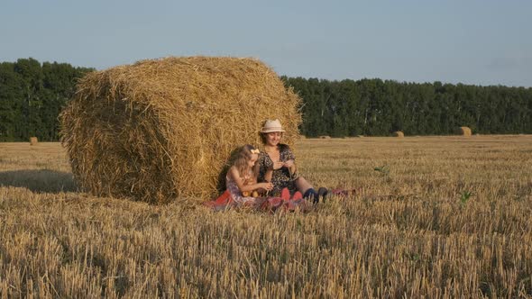 Woman with Little Daughter Relaxing Near Hay Bale alt