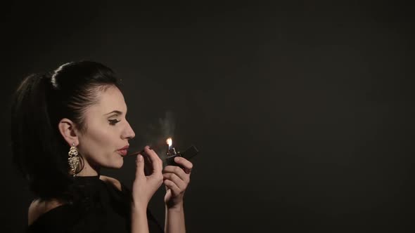 Beautiful Woman Lights a Cigarette on a Black Background alt