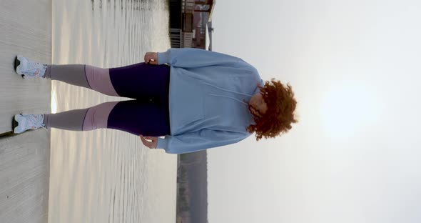 beautiful curly girl with red hair stretches her neck turning her head to the sides alt