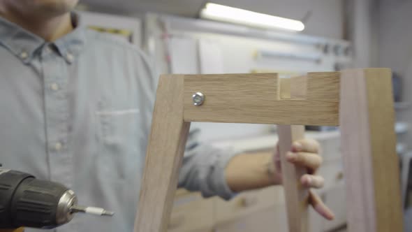 Unrecognizable Carpenter Tightening Screws with Powered Drill alt