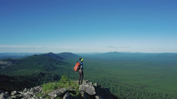 Aerial View of Young Traveller on the Mount Edge with Red Backpack