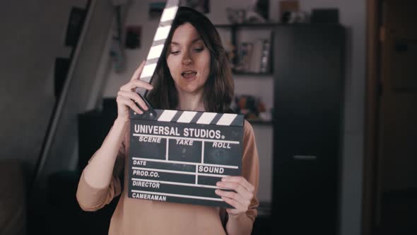 A beautiful girl holds a Clapperboard in her hands. Claps. Clicks. Winks at the camera. Flirting,