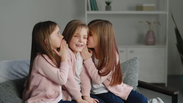 Three Sisters Triplets Identical Same Little Girls Children Sitting on Couch at Home in Living Room alt