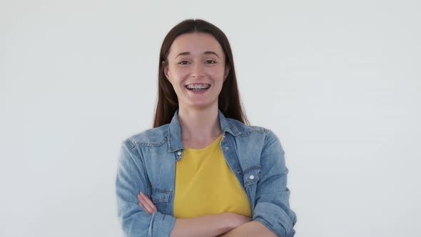 Confident Girl Laughs on White Background Looks at Camera with Arms Across Chest alt