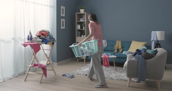 Frustrated housewife collects clothes from the ground, concept of home mess