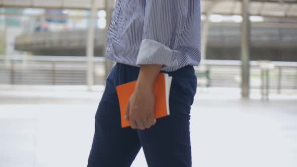 Portrait caucasian businessman hand holding a book walking on the street urban city.