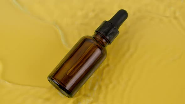 Bottle of Cosmetic Oil Sunlight Ptotection in Water Splash on Yellow Background