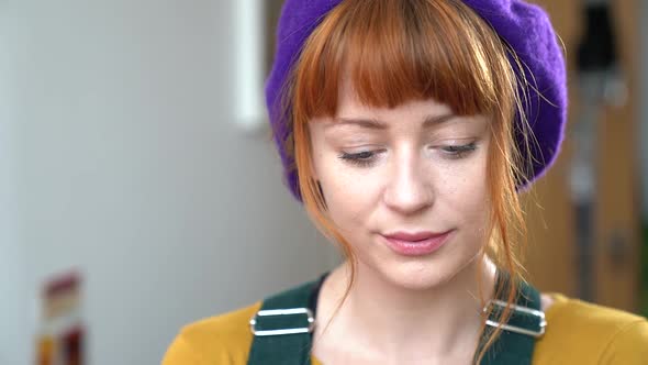 Close up Of Caucasian Woman with Red Hair and Blue Eyes, Purple Beanie Smiling to Camera