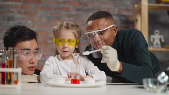 Little Girl Student Adjusts Funnel and Stirs Material in Lab alt
