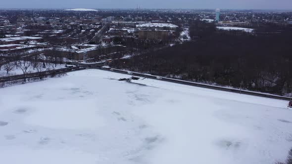 An aerial view from a drone, over a long lake during sunrise on a cloudy morning. The camera truck r alt