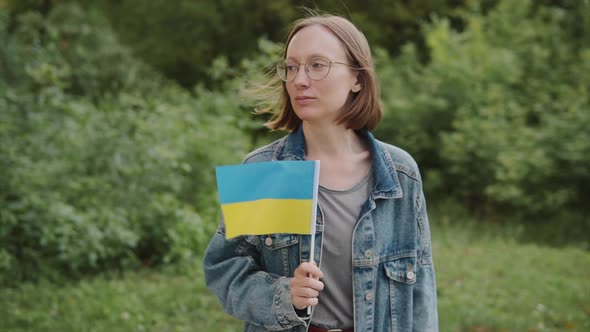 Young Woman Activist with the Flag of Ukraine on the Street Looks at the Camera
