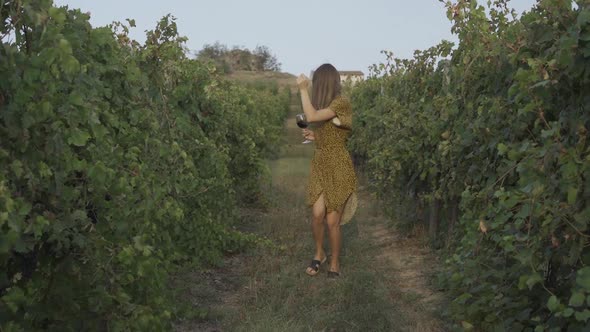 Happy Woman Dancing In Vineyard With Glass Of Wine