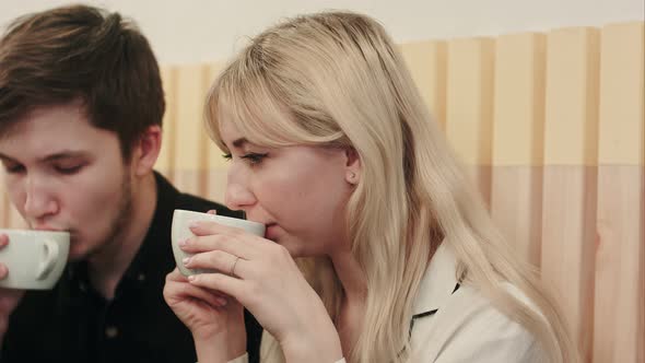 Portrait of Young Couple Talking Seriously and Drinking Coffee at a Coffee Shop