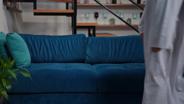 Middle Eastern Man Entering Living Room Sitting Down on Cozy Couch Relaxing alt