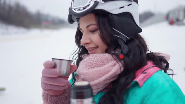 Closeup of Happy Woman Smelling and Drinking Tea at Winter Ski Resort in Slow Motion alt