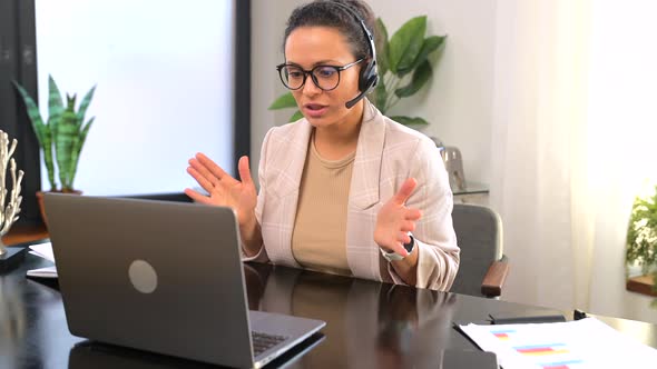 Smiling Female Call Center Employee Using a Headset and Laptop for Online Communication