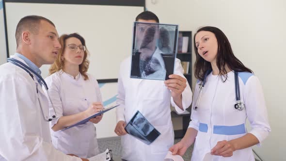 Team of Four Doctors Discusses the Results Chest X-Ray Scan of Patient inConsulting Room of Hospital alt