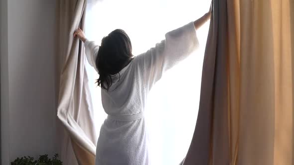 A Girl in a White Coat Opens the Curtains. In the Morning Stretch By the Window. Good Sunny