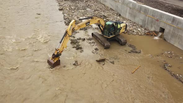 Yellow dredge Excavator working in the mountain river, scooping excavator bucket. Extracting gravel