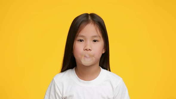 Little Korean Girl Chewing And Blowing BubbleGum Over Yellow Background ...