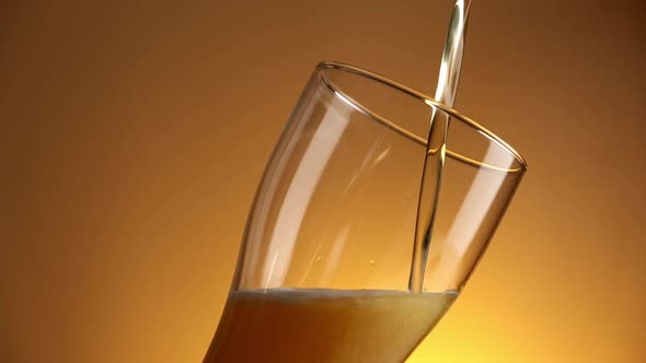 Beer is Pouring Into Glass on Golden Background