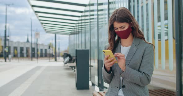 Brunette Girl in Cotton Mask Checking News or Browsing Internet, Millennial Woman in Protection alt