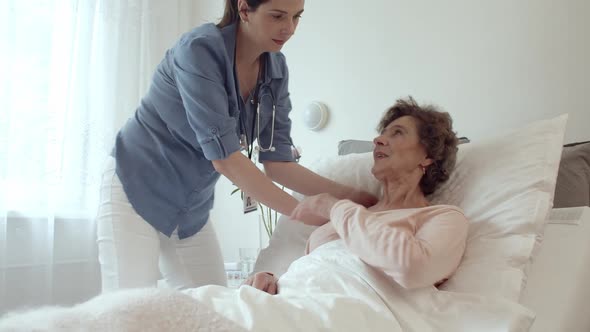 Home Nurse Making Bed of Elderly Female Patient
