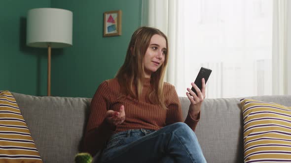 Young Girl Is Sitting on a Sofa and Talking on a Video Call