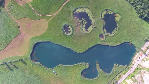 Aerial view of lakes on a grass meadow alt